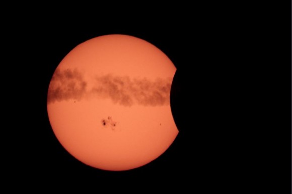 The solar eclipse on October 23, 2014, showing the Sun dotted by sunspots and airplane contrails. Credit and copyright: Greg Hogan.