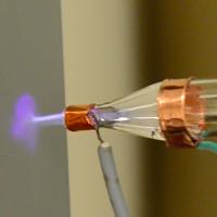 Image of the nozzle spraying a jet of nanoparticles, with the helium plasma on. Credit: NASA Ames Research Center