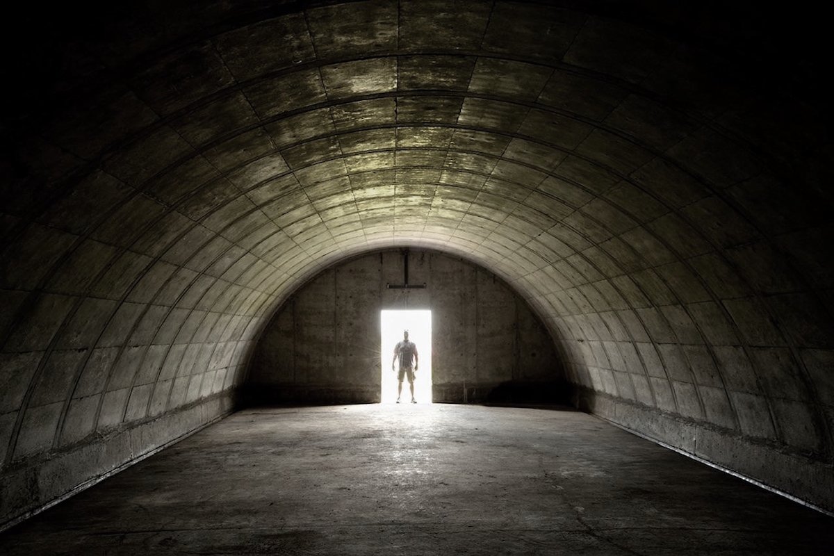 A man stands in the brightly-lit doorway of one of Vivos' dark bunkers, outfitted to help those with enough money to survive a doomsday scenario.
