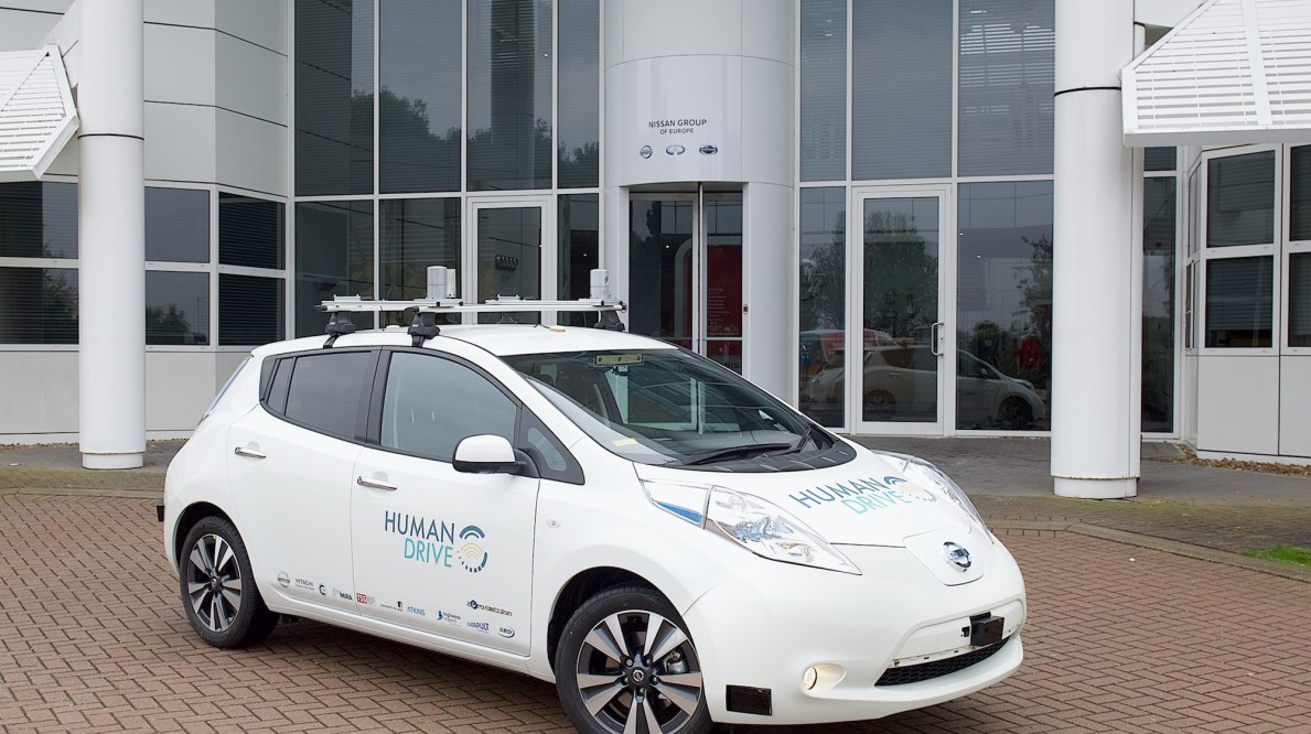 The HumanDrive Initiative's autonomous car, a while vehicle with a roof rack and a similar design to a Prius. This vehicle is slotted for a 200-mile self-driven test drive in 2019.