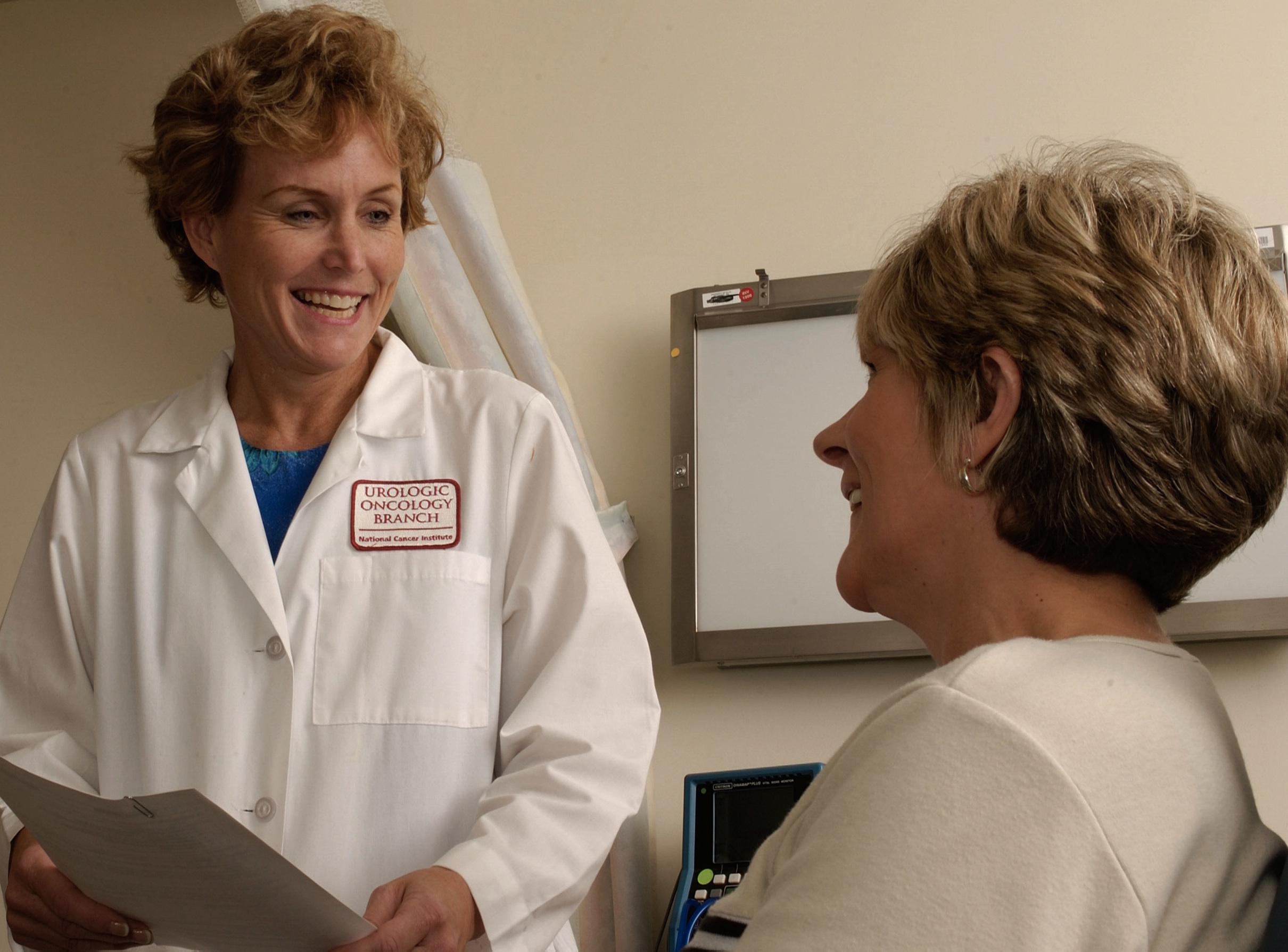 A white female doctor discussing medical data with a white female patient.