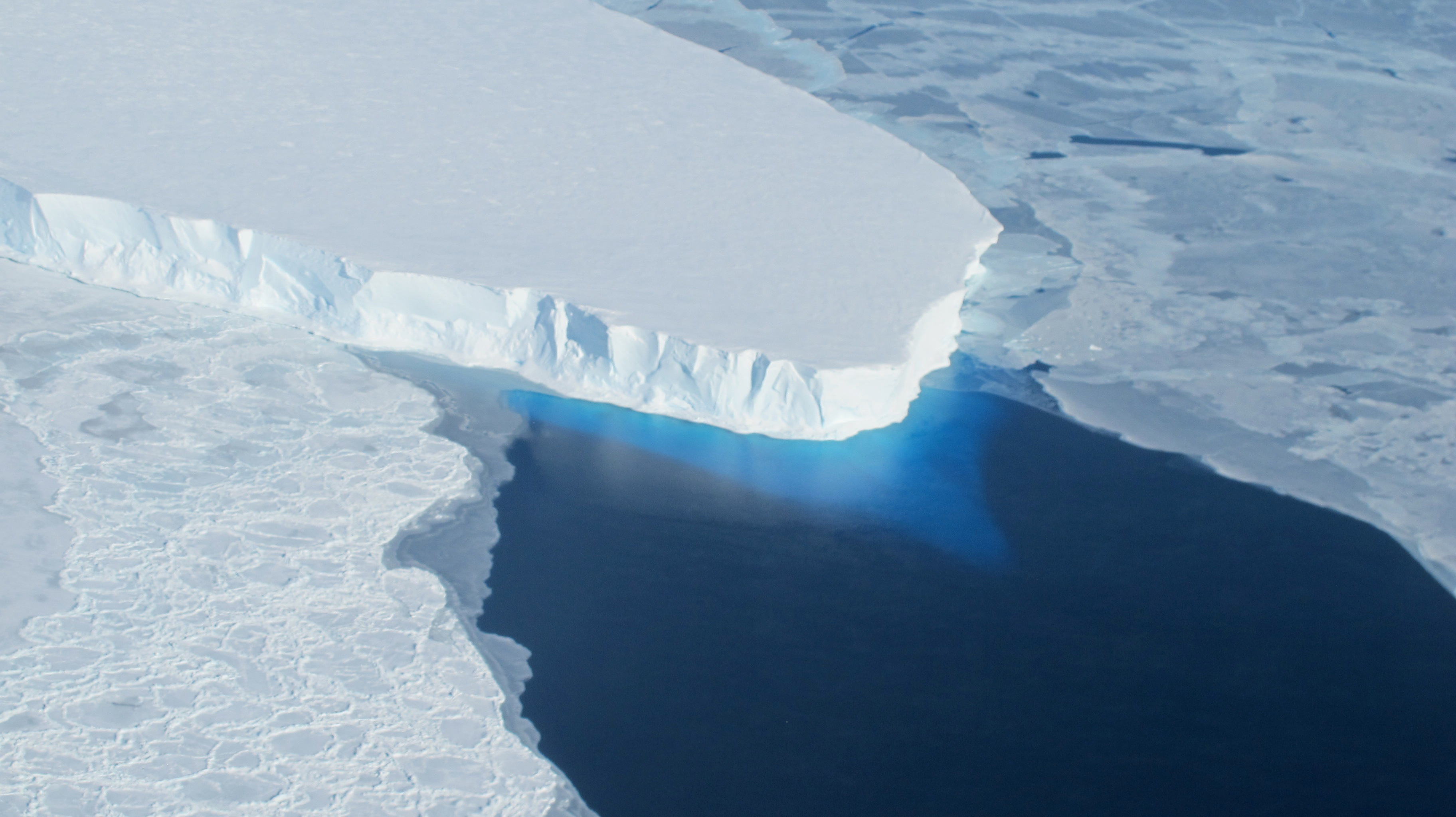 The Thwaites Glacier, shown here as a massive tongue of ice jutting out over blue water.