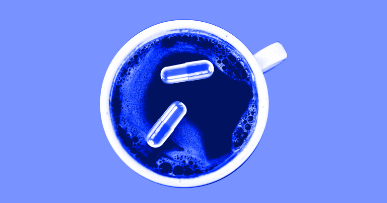 Some pills float in a blue tinted cup of coffee