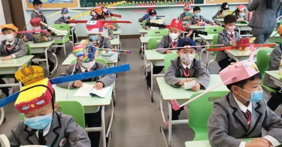 Images show Chinese school children wearing adorable hats with two long flaps on either sides that ensure they're social distancing properly.