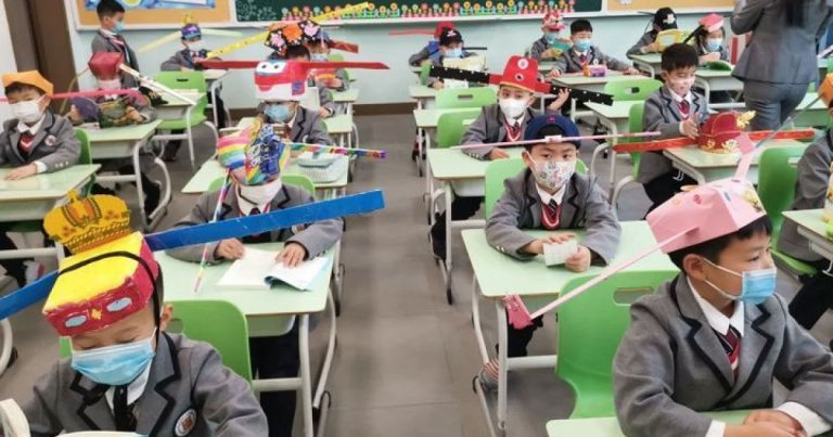 Images show Chinese school children wearing adorable hats with two long flaps on either sides that ensure they're social distancing properly.