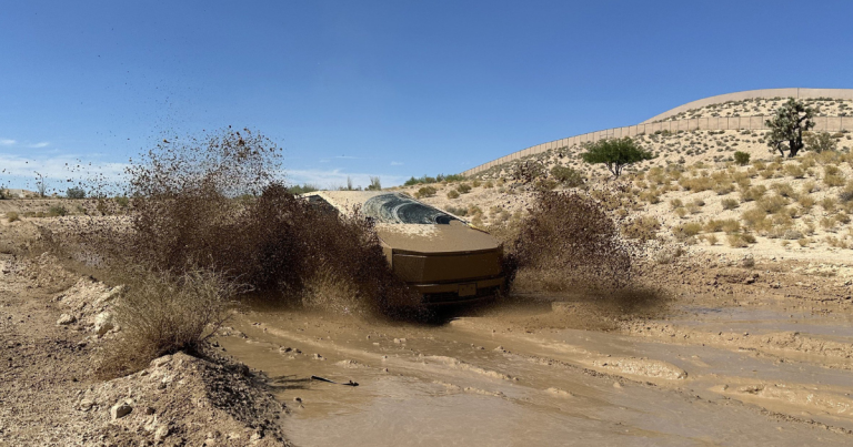A Tesla cybertruck driving through mud in a desert terrain.