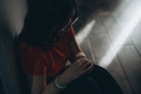 Upset teen girl sit on floor sadly look out window worried about teenage problem at school and communication with parent. Worried girl tensely suffer about bullying at school, unrequited love with boy