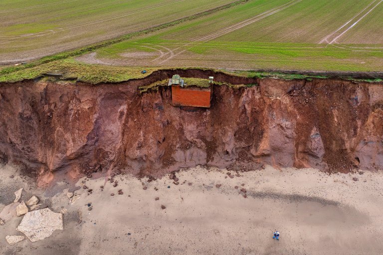 A nuclear bunker is hanging off the edge of a crumbling cliff face that's been eroded by the constant assault of the sea.