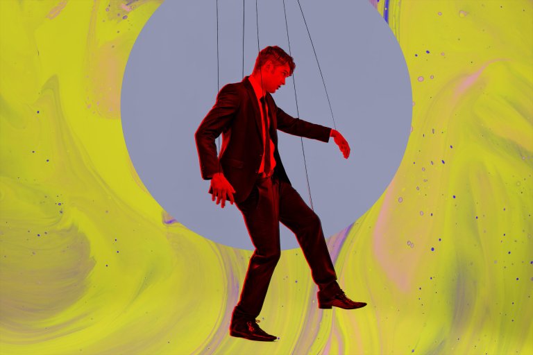 A man in a black suit and tie is depicted as a marionette puppet, suspended by strings. He is highlighted with a red outline and positioned against a large gray circle on a vibrant yellow and purple marbled background.