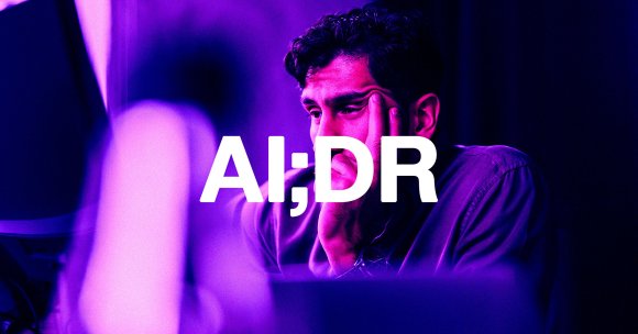 A man with dark curly hair resting his face on his hand, looking thoughtful or concerned, illuminated by purple and pink lighting. The large white text "AI;DR" is overlaid across the center of the image.