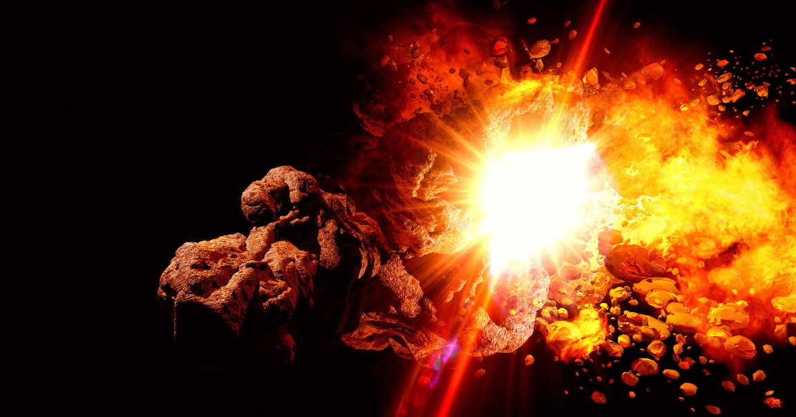 A large asteroid or rocky space object is shown exploding in space, with bright fiery flames and debris scattering outward against a dark background. The explosion emits intense light and heat, illuminating the surrounding fragments.
