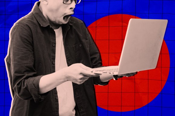 A person wearing glasses and a dark shirt over a light t-shirt is holding a laptop with both hands, looking at the screen with a surprised or shocked expression. The background features a blue grid pattern with a large red circle.