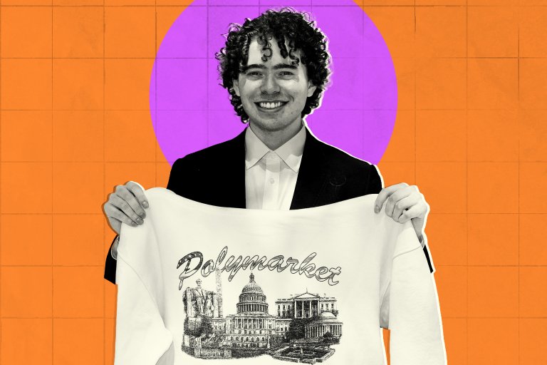Polymarket CEO Shayne Coplan shown wearing a black suit and white shirt holds up a white sweatshirt featuring a detailed black illustration of Washington, DC with the word "Polymarket" written above the illustration in a stylized script. The background is orange with a large purple circle behind the man's head.