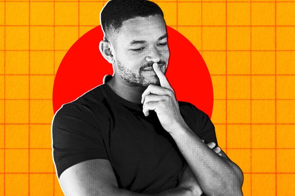 A thoughtful man with short hair and a beard, wearing a black t-shirt, is posed with one arm crossed and his other hand touching his lips. The image is stylized in black and white with a white outline around the man, set against a bright orange background with a red circle behind his head and a subtle grid pattern.