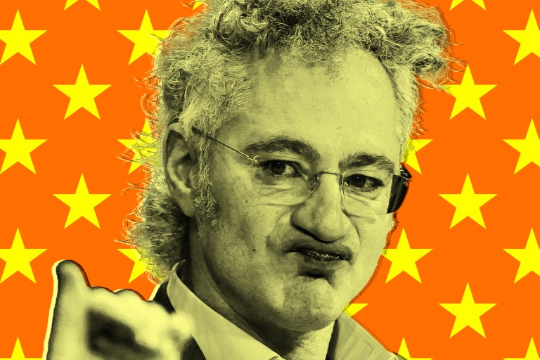 A close-up of Palantir CEO Alex Karp, with curly hair and glasses, making a puckered facial expression. The image has a yellowish tint, and the background is bright orange with a pattern of yellow stars. Karp is wearing a collared shirt and a jacket.