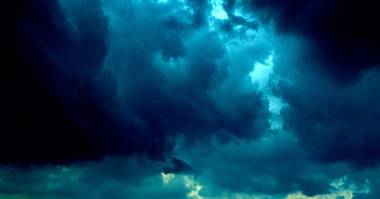 Dark, dense storm clouds with a blue-green tint fill the sky, creating a dramatic and moody atmosphere.