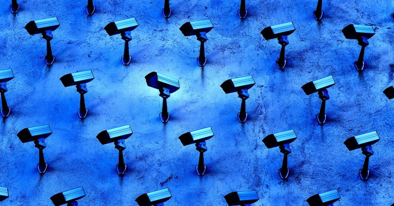 Multiple security cameras mounted on a textured blue wall, arranged in a grid pattern, all facing in roughly the same direction.