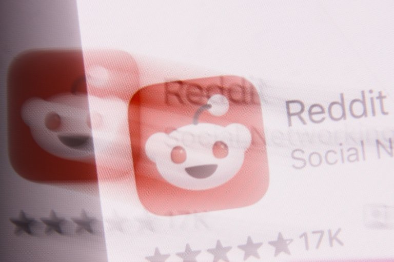 The image shows a blurred and double-exposed view of the Reddit app icon, which features a white smiling alien face with an antenna on a red background.