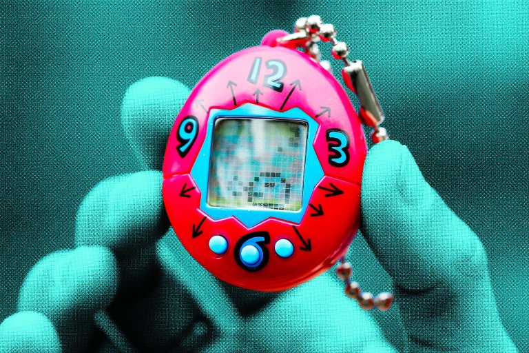 A close-up of a hand holding a red digital pet keychain toy with a small screen in the center. The toy has a clock-like design with numbers 12, 3, 6, and 9 around the screen and small arrows pointing outward. It also has three blue buttons below the screen and a silver ball chain attached at the top. The hand is wearing a teal glove.
