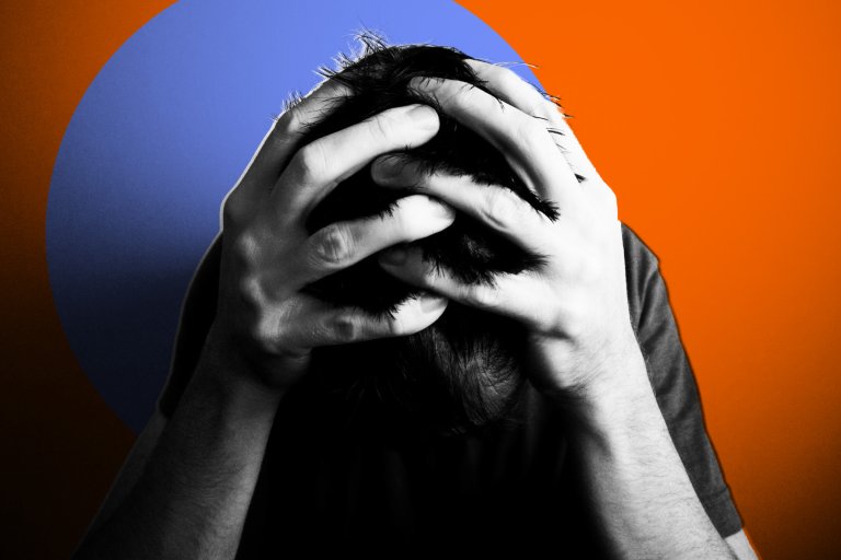A person with dark hair is holding their head with both hands, fingers interlaced in their hair, suggesting stress or frustration. The image is in black and white except for a large blue circle and an orange background behind the person.