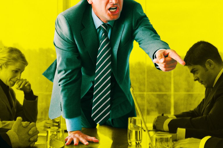 A man in a suit and striped tie is leaning forward on a table, angrily pointing and shouting. Around the table, other people in business attire appear tense and withdrawn, with one woman looking down pensively and a man sitting with his head bowed. The background is tinted yellow, emphasizing the intense atmosphere. Glasses of water and a laptop are on the table.