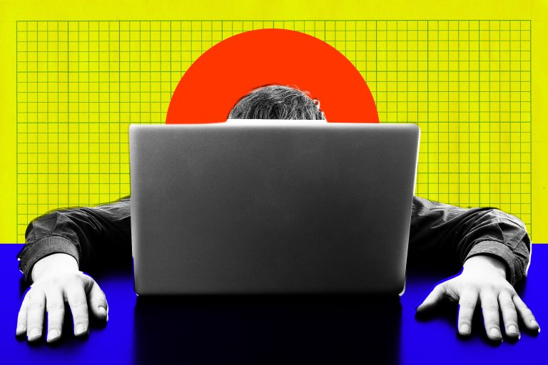A person with gray hair is sitting behind a laptop, with only the top of their head visible above the screen.