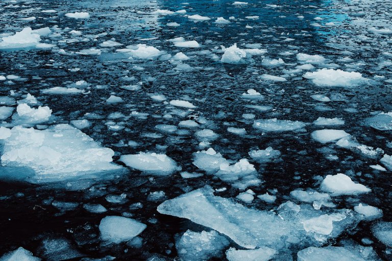 Chunks of ice floating on dark, cold water, creating a fragmented icy surface. The ice pieces vary in size and shape, scattered across the water.