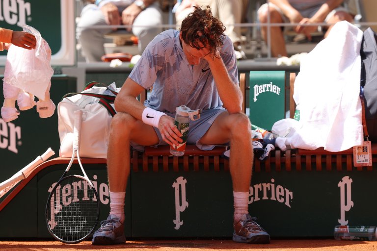 Jannik Sinner of Italy looks hot and sweaty as he drinks water during a break at Roland Garros.