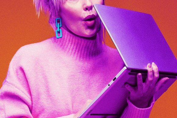 A person wearing a pink turtleneck sweater and turquoise chain-link earrings is holding a silver laptop partially open. The background is orange, and the image has a purple-pink color overlay effect. The person’s mouth is slightly open as if speaking or reacting.