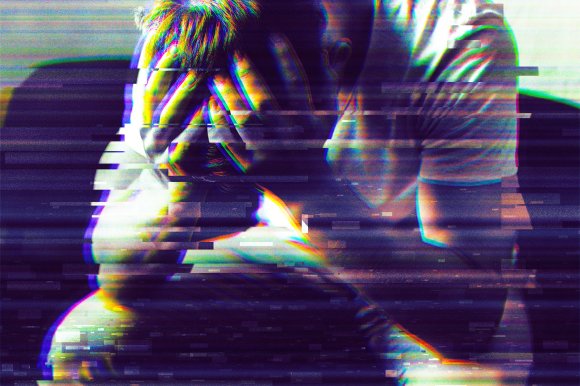A person sitting with their head in their hands, appearing distressed or overwhelmed. The image has a glitch effect with horizontal digital distortion and color separation, giving it a fragmented and intense visual style. The person is wearing a light-colored shirt and has short hair.