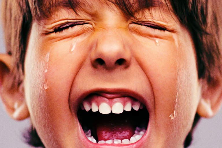 Close-up photograph of a young boy crying and screaming.