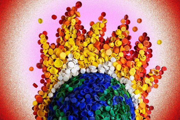 A colorful arrangement of plastic bottle caps forms a globe at the bottom with blue and green caps, surrounded by a white ring of caps, and topped with a flame-like burst of caps in yellow, orange, and red hues against a pink and red gradient background.