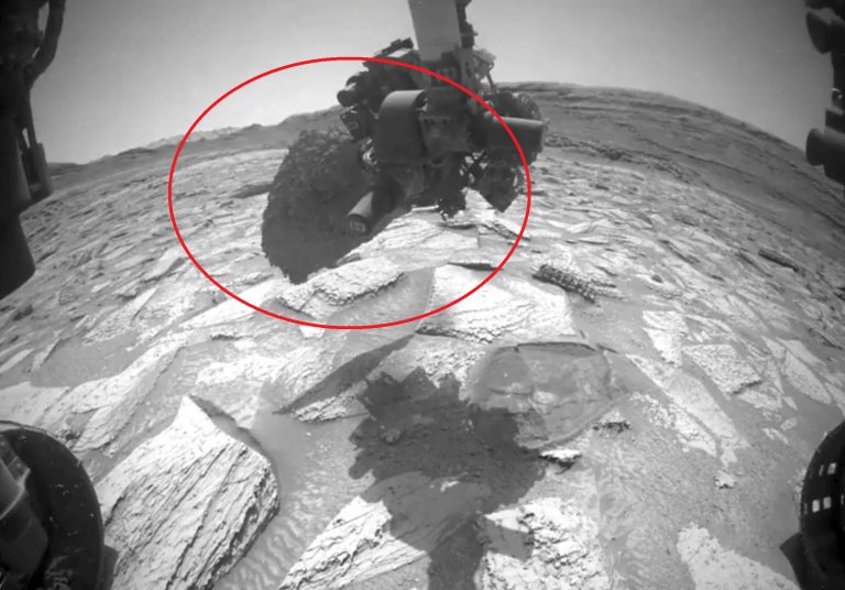 The image shows a robotic arm on NASA's Curiosity Mars rover that has become stuck inside a rock on the Red Planet.