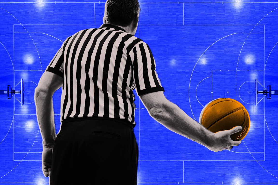 A basketball referee shown from behind holding a basketball in his right hand over a field of blue.