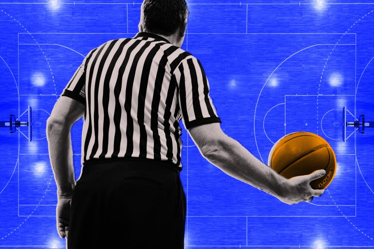 A basketball referee shown from behind holding a basketball in his right hand over a field of blue.
