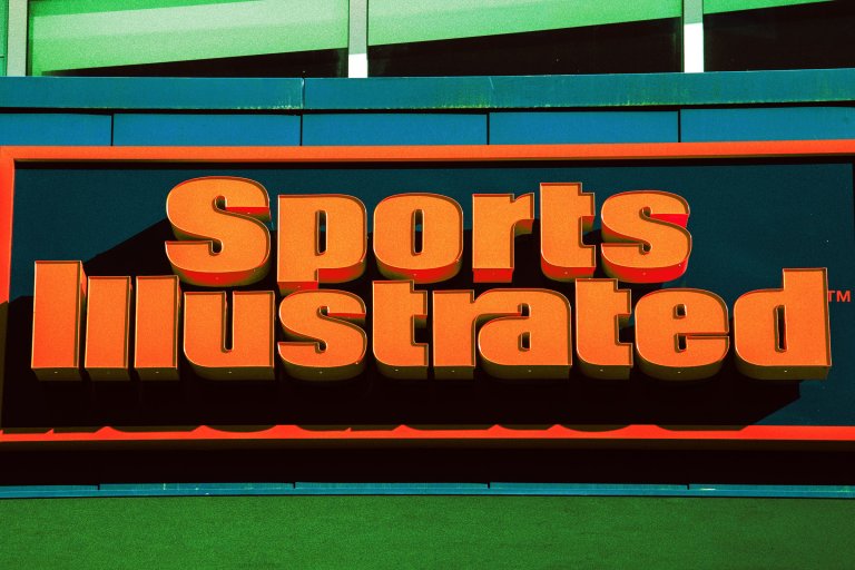 Large, bold, orange 3D letters spelling "Sports Illustrated" on a dark background with an orange border, mounted on a building facade with green and blue panels above and below.