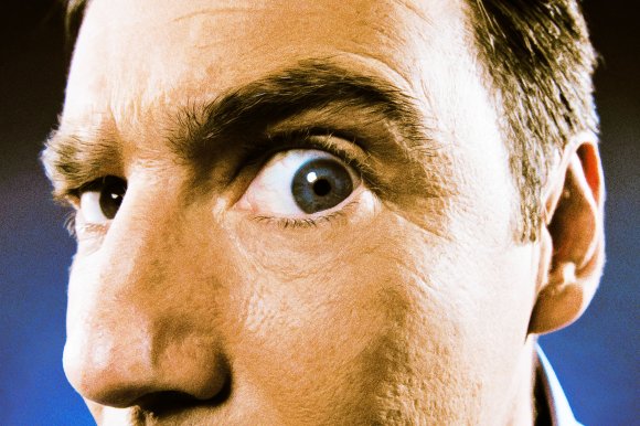 Close-up photograph of a suspicious man closely investigating the viewer.
