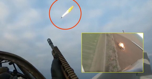 A person wearing a black glove is aiming a rifle with a mounted ammunition belt towards the sky. A drone is seen in mid-air with a trail of smoke and fire, highlighted by a red circle. In the bottom right corner, there is an inset image outlined in yellow showing an explosion on the ground near a dirt road, viewed from above. The background is a cloudy sky.