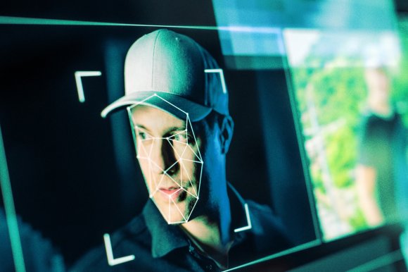 Image of a man on a computer screen whose face is being scanned and identified for fakery.