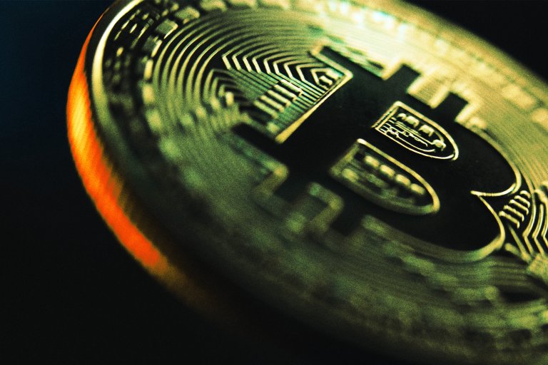 Photograph of an enlarged bitcoin fading into darkness.