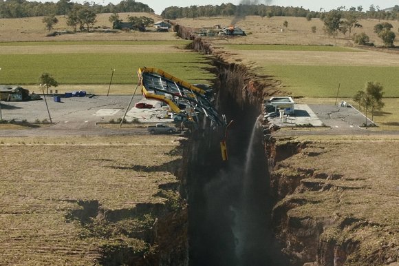 A still from the 2015 disaster film San Andreas, dramatically showing the earth split in half along a fault line.
