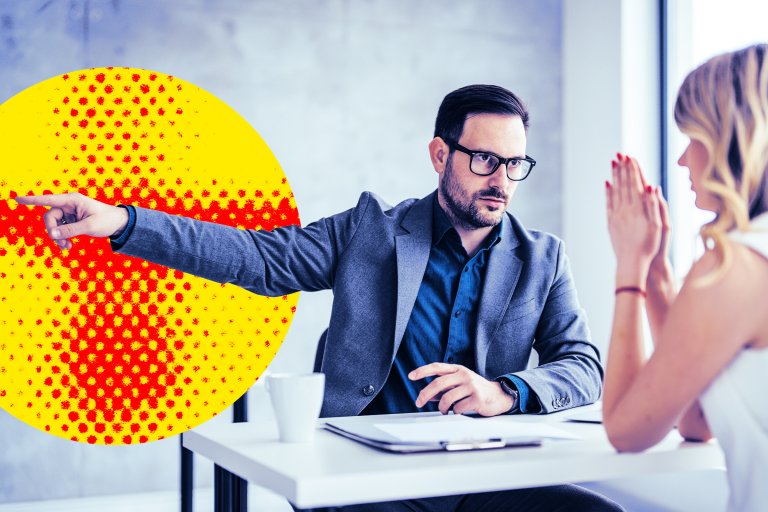 A man wearing glasses and a gray blazer is sitting at a white table, pointing to his left with a serious expression. Across from him, a woman with blonde hair and red-painted nails has her hands clasped together near her face. A yellow and red halftone circle graphic is overlaid on the left side of the image.