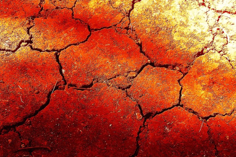 A color-treated photograph of dry, cracked soil.