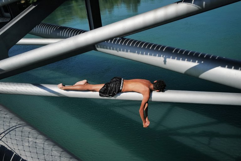 A teenager lays on the Passerelle de la Paix bridge, prior to jump in the Rhone river, in Lyon, southern France, on June 25, 2026 during a heatwave in France and Europe.