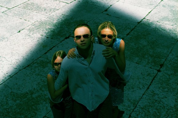 A family looks up at a large structure in that casts a shadow over them.