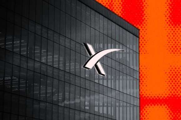 A modern glass building facade with a large white SpaceX logo prominently displayed in the center. The right side of the image features a bright orange background with a dotted pattern. The building's reflective windows show interior lighting and structural elements.