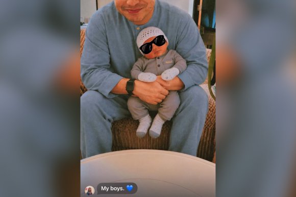 A screenshot of an AI doctored image featuring a man holding a digitally inserted child.
