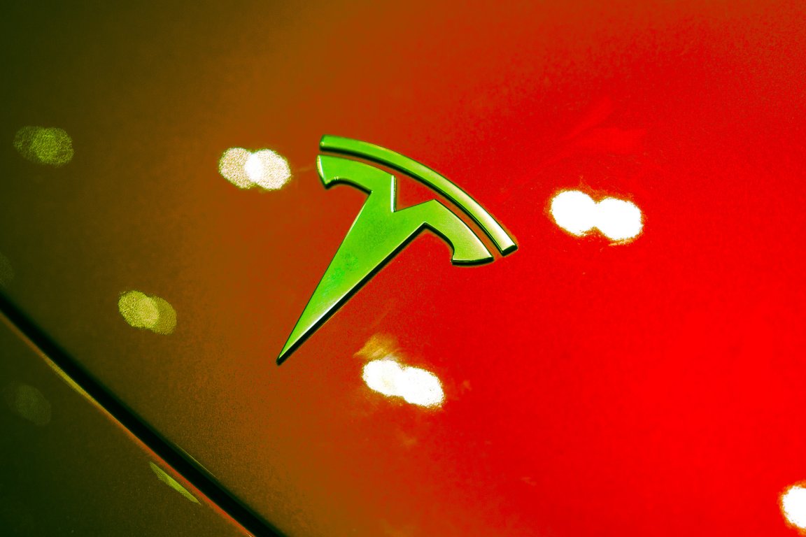 A color treated photograph of a Tesla logo hood ornament.