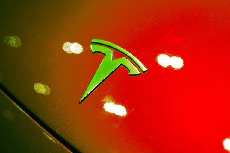 A color treated photograph of a Tesla logo hood ornament.