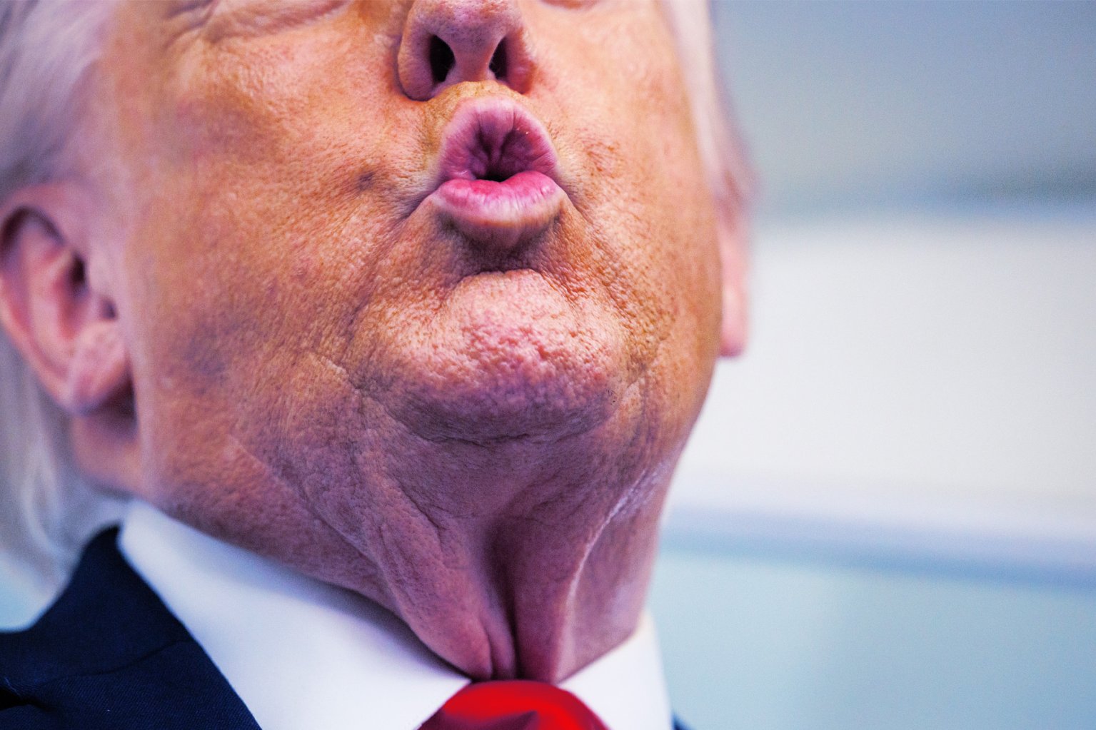 A close-up photograph of U.S. President Donald Trump speaking to reporters, his mouth puckered in an "o" sound.